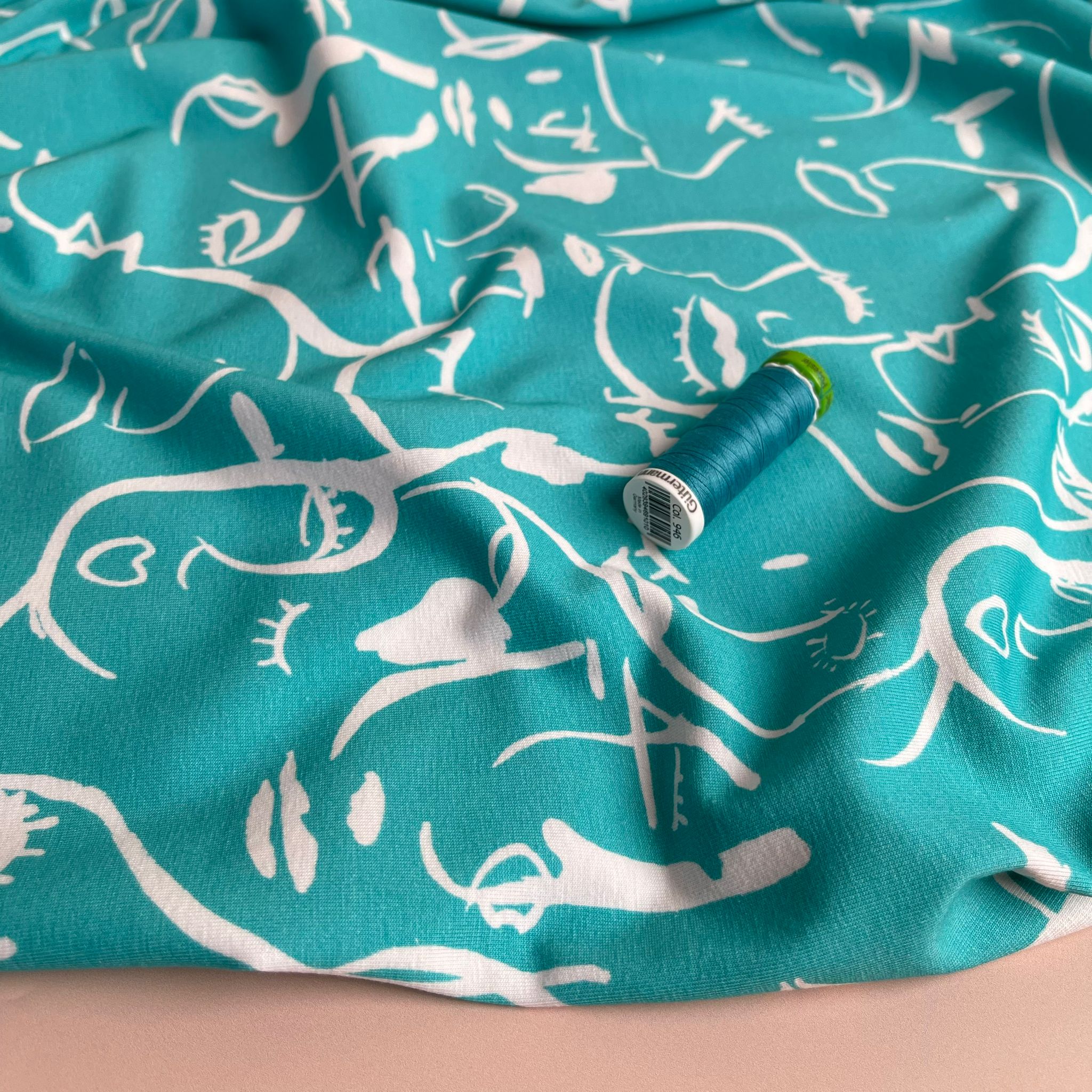 Danish Design - Painted Faces on Turquoise Cotton Jersey Fabric